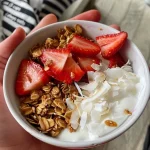 A close-up view of strawberry shortcake yogurt bowls topped with fresh strawberries and nuts.