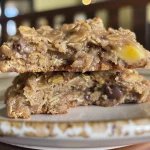 Side view of freshly baked banana oatmeal cookies on a wooden table.