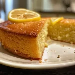 Close-up of a moist lemon yogurt cake with a golden crust and lemon zest garnish.