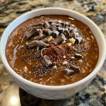 Close-up view of chocolate chia pudding topped with chia seeds and a drizzle of maple syrup.