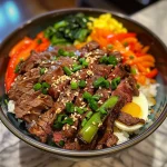 A close-up side view of a Korean-style beef rice bowl topped with fried eggs and garnished with sesame seeds.
