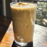 Close-up side view of a creamy peanut butter smoothie in a glass.
