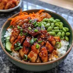 Close-up view of a bowl filled with savory Korean BBQ chicken, rice, and colorful vegetables.
