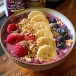 A vibrant acai smoothie bowl topped with sliced bananas and berries.