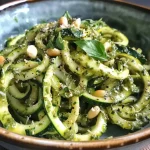 Close-up of zoodles topped with vibrant green pesto.