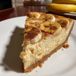 A slice of Baked Almond Banana Cheesecake with a creamy texture and almond crust.