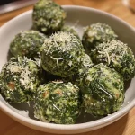 Close-up of golden-brown spinach balls on a white plate.