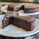 A close-up side view of a flourless black cocoa and chia Greek yogurt cake on a plate.