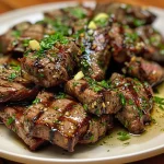 Close-up view of juicy garlic butter steak bites garnished with parsley.