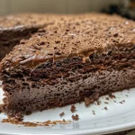 Close-up side view of a moist gluten-free chocolate cake, showcasing rich textures and layers.