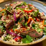 Close-up view of a colorful Moroccan beef and couscous salad with fresh vegetables.