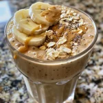 Close-up side view of a creamy Peanut Butter Oat Smoothie in a glass.