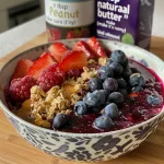 Close-up view of a colorful berry crumble topped with oats and nuts.