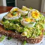 A close-up view of avocado egg salad toast topped with green onions on sourdough bread.