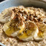 Close-up of creamy Banana Almond Overnight Oats topped with sliced banana and a drizzle of honey.