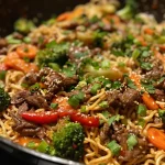 Close-up of a savory beef stir fry with colorful vegetables and noodles.