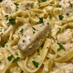 Close-up view of Chicken Fettuccine Alfredo with a creamy sauce and grilled chicken.