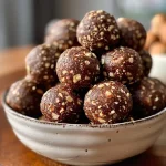 ['Close-up view of chocolate hazelnut energy balls arranged on a plate.', 'Side view of several chocolate hazelnut energy balls with a rich, textured surface.', 'Juicy chocolate hazelnut energy balls displayed on a wooden board.', 'Cluster of energy balls made with chocolate and hazelnuts, showcasing their chewy texture.']
