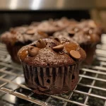 ['Close-up side view of a gluten-free double chocolate muffin with melting chocolate chips.', 'Detailed shot of a moist, dairy-free double chocolate muffin showcasing its rich texture.', 'Side view of luscious gluten-free double chocolate muffins with a glossy chocolate finish.', 'Close-up of decadent chocolate muffins filled with semi-sweet chocolate chips, gluten-free and dairy-free.']