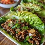 Close-up view of juicy Korean ground beef in lettuce wraps with garnishes.