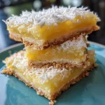 ['Close-up of a golden lemon-coconut bar, showcasing its flaky texture and glossy lemon topping.', 'Deliciously baked lemon-coconut bars, highlighting the coconut flakes and lemon zest on the surface.', 'Side view of moist lemon bars with a coconut finish, resting on a white plate.', 'Juicy lemon-coconut bars, displaying a rich, bright yellow filling and a crumbled coconut crust.']