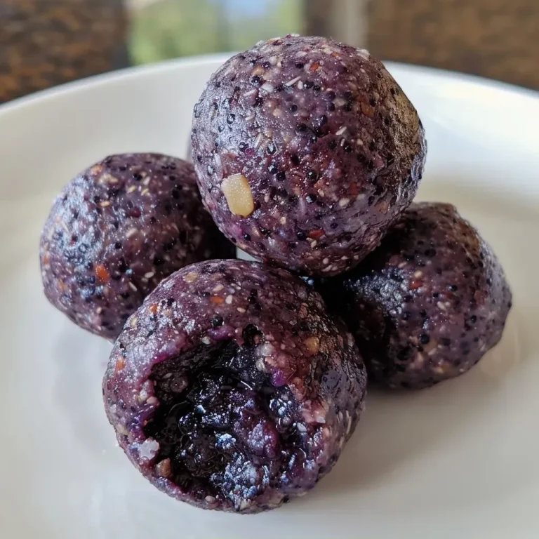 ['Close-up view of Paleo Blueberry Bliss Balls on a textured surface, showcasing their round shape and rich color.', 'Side view of juicy Paleo Blueberry Bliss Balls with a shiny exterior, highlighting the vibrant blueberry hue.', 'A cluster of Paleo Blueberry Bliss Balls, depicting their raw texture and inviting appearance.', 'Detailed shot of Paleo Blueberry Bliss Balls, emphasizing their moist surface and berry-infused color.']