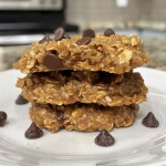 ['Close-up of Peanut Butter Banana Oatmeal Cookies displaying a golden-brown texture.', 'Side view of chewy oatmeal cookies with visible chocolate chips and oats.', 'Deliciously baked banana oatmeal cookies featuring a rich peanut butter color.', 'Freshly made oatmeal cookies with a mix of peanut butter and banana.']