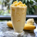 ['A refreshing Piña Colada Smoothie in a glass with a slice of pineapple on the rim.', 'A close-up view of a creamy Piña Colada Smoothie with crushed pineapple and coconut milk.', 'A side view of a vibrant yellow Piña Colada Smoothie topped with a pineapple slice.', 'A delicious Piña Colada Smoothie in a glass, showcasing its rich texture and tropical color.']