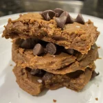 ['Close-up of protein cookies featuring a rich, golden-brown color and chocolate chip topping.', 'Side view of soft, chewy protein cookies with a glossy finish and melted chocolate chips.', 'A plate of delicious protein cookies showcasing their texture and chocolate chunks.', 'Juicy protein cookies displayed with a tempting, slightly gooey appearance from chocolate chips.']