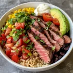 ['Close-up of a bowl filled with flank steak, rice, beans, and colorful toppings.', 'Side view of a hearty flank steak bowl showcasing various fresh ingredients.', 'Juicy flank steak bowl topped with avocado, salsa, and cilantro, served in a white dish.', 'Vibrant bowl of quick flank steak with rice, black beans, and diced tomatoes.']