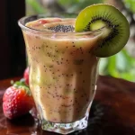 ['A colorful smoothie in a clear glass with kiwi slices and strawberries on the side.', 'A refreshing kiwi smoothie displayed beside fresh fruit slices and a spoonful of chia seeds.', 'A close-up view of a tropical smoothie with vibrant colors, showcasing its thick texture and fresh ingredients.', 'A side view of a delicious smoothie, highlighting the green kiwi and red strawberry elements.']