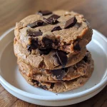 ['Close-up side view of vegan protein chocolate chip cookies with a soft texture.', 'Side view of warm, gooey vegan chocolate chip cookies displaying chocolate chunks.', 'Juicy vegan protein cookies stacked, showcasing their moist interior and chocolate pieces.', 'Vegan chocolate chip cookies highlighting a golden-brown exterior and melted chocolate.']