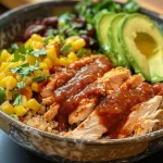 ['Close-up view of a BBQ chicken quinoa bowl with vibrant colors.', 'Side view of a quinoa bowl topped with chicken, corn, and avocado.', 'A colorful bowl featuring BBQ chicken, quinoa, and fresh ingredients.', 'Juicy BBQ chicken quinoa bowl with visible layers of ingredients.']