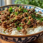 ['Close-up shot of ground beef and rice with a sprinkle of parsley and pine nuts.', 'Side view of a plate featuring a delicious ground beef and rice dish with chickpeas.', 'Juicy ground beef and basmati rice garnished with fresh herbs and nuts.', 'A vibrant bowl of ground beef and rice highlighting ingredients like onion and chickpeas.']