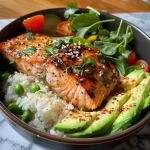 ['Close-up of a Lemon Pepper Salmon Rice Bowl with colorful vegetables and rice.', 'Side view of a delicious Lemon Pepper Salmon Rice Bowl featuring salmon, rice, and fresh greens.', 'Juicy Lemon Pepper Salmon atop a bed of rice, garnished with fresh vegetables.', 'Aesthetic presentation of Lemon Pepper Salmon Rice Bowl showcasing vibrant ingredients.']