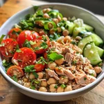['Close-up view of a Mediterranean Brown Rice and Tuna Bowl featuring colorful ingredients.', 'Side view of a Mediterranean-inspired meal with brown rice, tuna, and fresh vegetables.', 'Juicy tuna bowl with cherry tomatoes, cucumbers, and chickpeas on a wooden table.', 'Delicious Mediterranean bowl showcasing brown rice, tuna, and a drizzle of dressing.']