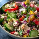 ['A vibrant Mediterranean Tuna Salad featuring colorful ingredients in a bowl.', 'A close-up view of a fresh Mediterranean Tuna Salad with visible chunks of tuna and vegetables.', 'A side angle of a Mediterranean Tuna Salad showcasing bell peppers, cucumbers, and capers.', 'A detailed shot of Mediterranean Tuna Salad, highlighting the mix of colorful ingredients and textures.']