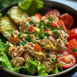 ['Close-up view of a bowl of mustard tuna salad with cherry tomatoes and parsley.', 'Side view of a vibrant mustard tuna salad featuring chopped pickles and lettuce.', 'Juicy mustard tuna salad in a clear dish, showcasing bright cherry tomatoes and fresh herbs.', 'Detailed photo of mustard tuna salad highlighting its colorful ingredients and textures.']