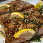 ['Juicy seared tuna steaks garnished with herbs and lemon wedges.', 'Close-up view of perfectly cooked tuna steaks topped with garlic herb butter.', 'Succulent seared tuna steaks arranged elegantly with fresh herbs and lemon slices.', 'A side view of glistening tuna steaks with a rich garlic herb butter topping.']
