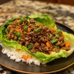 ['Close-up view of Teriyaki Ground Beef Lettuce Wraps on a plate, showcasing vibrant colors and textures.', 'Juicy Teriyaki Ground Beef wrapped in fresh butter lettuce leaves, garnished with green onions.', 'Side view of a delicious lettuce wrap filled with teriyaki ground beef and stir-fry vegetables.', 'A plate of Teriyaki Ground Beef Lettuce Wraps with visible ingredients, presented in a vibrant setting.']