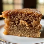 ['Close-up view of a moist applesauce cake slice topped with a light glaze.', 'Side view of a deliciously baked applesauce cake with a golden-brown crust.', 'Juicy slice of applesauce cake revealing a tender crumb and visible ingredients.', 'Freshly baked applesauce cake displayed on a plate with a rustic background.']