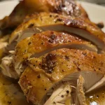 ['Close-up view of a juicy boneless turkey breast cooked in a Crock Pot.', 'Side view of a tender turkey breast with a rich brown gravy sauce.', 'Highlighted image of a moist turkey breast garnished with herbs.', 'Detailed close-up of a flavorful turkey breast dish from a slow cooker.']