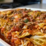 ['A close-up side view of a Crockpot Cabbage Roll Casserole, showcasing the layered ingredients.', 'Juicy and colorful Crockpot Cabbage Roll Casserole in a dish, with cabbage and meat visibly layered.', 'Side view of a Crockpot Cabbage Roll Casserole, highlighting its rich textures and vibrant colors.', 'A detailed close-up of a casserole dish filled with Crockpot Cabbage Roll Casserole, garnished and ready to serve.']