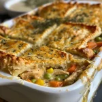 ['Close-up view of a golden-brown chicken pot pie casserole with biscuit topping.', 'Side view of a homemade chicken pot pie casserole filled with chicken, vegetables, and sauce.', 'Delicious and hearty chicken pot pie casserole with a flaky biscuit crust, fresh from the oven.', 'Juicy chicken pot pie casserole showcasing a creamy filling and golden biscuit topping.']