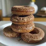 ['Close-up of a healthy apple cider protein donut with a glazed top.', 'Side view of a protein donut, showcasing a light brown color and a sprinkle of cinnamon.', 'Delicious-looking apple cider protein donut, highlighting its fluffy texture and healthy ingredients.', 'Juicy protein donut made with apple cider, presented in an inviting manner.']