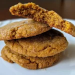 ['Close-up of healthy pumpkin sugar cookies on a white plate, showcasing a soft texture.', 'Side view of moist pumpkin sugar cookies with a golden-brown color, displayed on a rustic wooden table.', 'Deliciously baked healthy pumpkin sugar cookies stacked on top of each other, highlighting their chewy consistency.', 'Freshly made healthy pumpkin sugar cookies with visible spices and pumpkin purée, set against a colorful kitchen backdrop.']