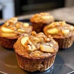 ['Close-up side view of a golden-brown protein apple cinnamon muffin with visible apple chunks.', 'Juicy apple cinnamon muffin showcasing a crumbly texture and a sprinkle of cinnamon on top.', 'Side view of a delicious protein-packed muffin with apple pieces and a soft, moist appearance.', 'Freshly baked apple cinnamon muffin with a crispy exterior and chunks of apple peeking through.']