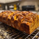 ['A close-up side view of a golden-brown Pumpkin Pecan Babka with visible pecan pieces.', 'Side view of a freshly baked Pumpkin Pecan Babka showcasing its spiral layers and texture.', 'Juicy Pumpkin Pecan Babka on a wooden surface, highlighting its rich colors and nutty topping.', 'Detailed side shot of a Pumpkin Pecan Babka, emphasizing the blend of pumpkin and pecan in the bread.']