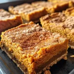 ['Close-up side view of delicious pumpkin pie bars with a golden crust.', 'Juicy pumpkin pie bars showing layers of creamy filling and crust.', 'Rich pumpkin pie bars with a glossy top, placed on a white background.', 'Sliced pumpkin pie bars showcasing texture and color contrast.']
