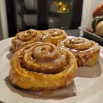 ['Close-up view of pumpkin spice cinnamon rolls drizzled with icing.', 'Side view of freshly baked pumpkin spice cinnamon rolls topped with frosting.', 'Delicious pumpkin spice cinnamon rolls on a plate, showcasing their fluffy texture.', 'Juicy pumpkin spice cinnamon rolls with a golden crust and creamy icing.']